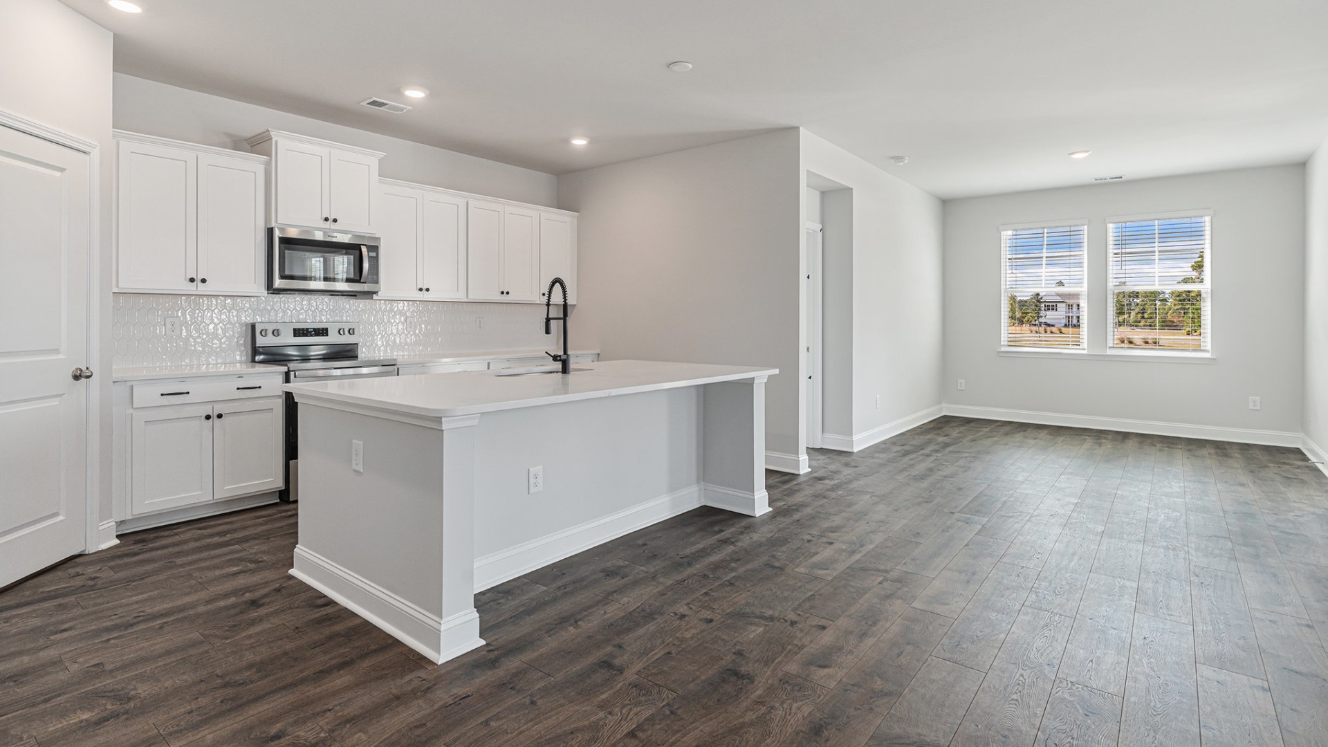 The open-concept kitchen shines with granite countertops, a stylish tile backsplash, a large island, and LVP flooring that extends through the main living areas.