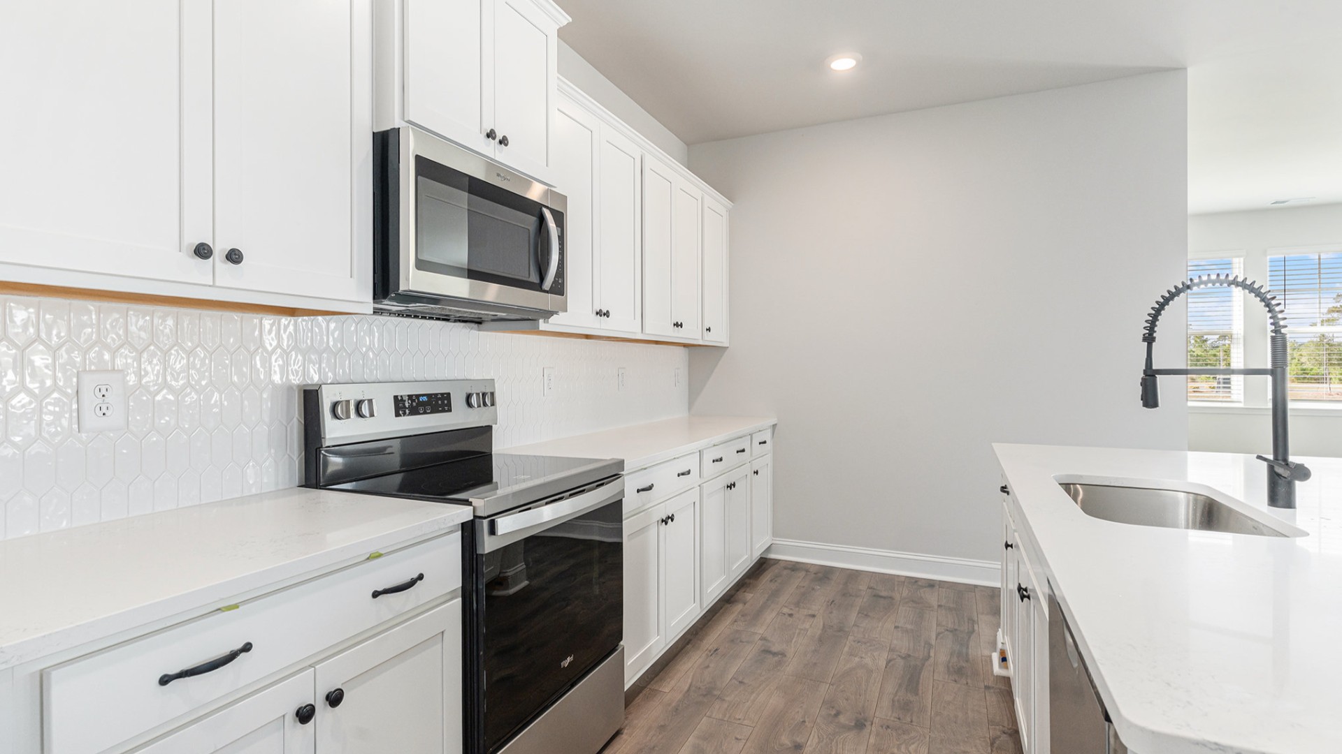 The open-concept kitchen shines with granite countertops, a stylish tile backsplash, a large island, and LVP flooring that extends through the main living areas.