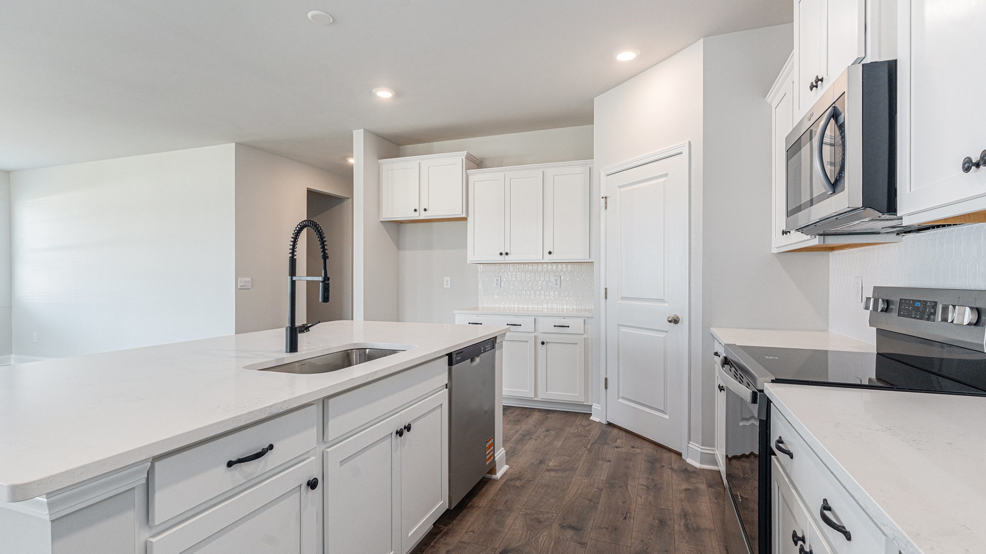 The open-concept kitchen shines with granite countertops, a stylish tile backsplash, a large island, and LVP flooring that extends through the main living areas.