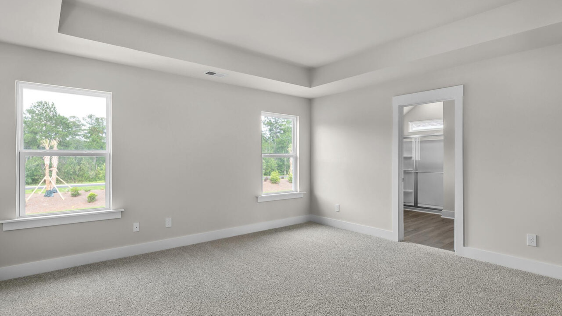 The primary suite features a sitting room, walk-in closet, trayed ceiling, a step-in 5-foot shower, dual vanity with granite countertops, and natural light in the bathroom