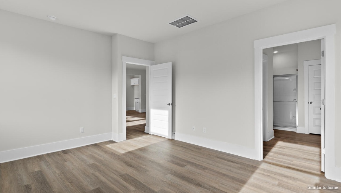 The primary suite, at the rear of the home, includes an en-suite bathroom with a walk-in closet, double vanity, and walk-in shower.