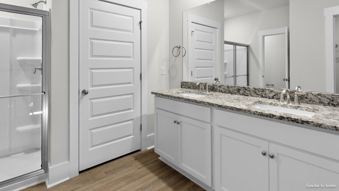 The primary suite, at the rear of the home, includes an en-suite bathroom with a walk-in closet, double vanity, and walk-in shower.