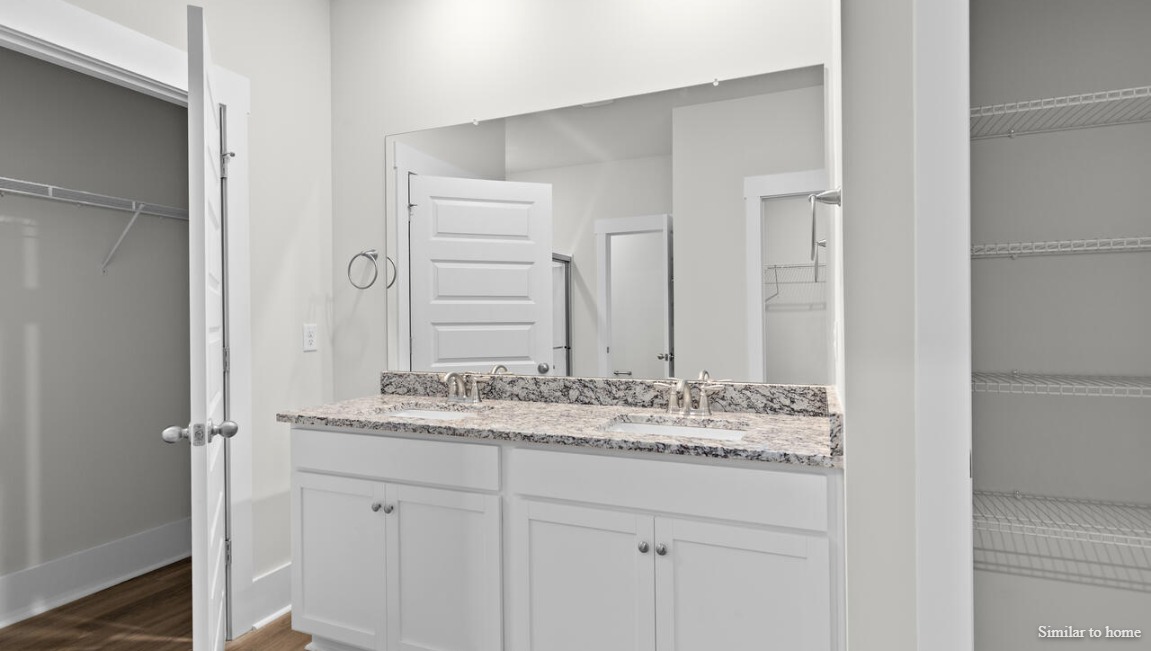 The primary suite, at the rear of the home, includes an en-suite bathroom with a walk-in closet, double vanity, and walk-in shower.