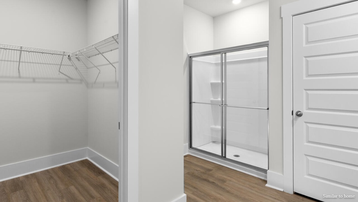The primary suite, at the rear of the home, includes an en-suite bathroom with a walk-in closet, double vanity, and walk-in shower.