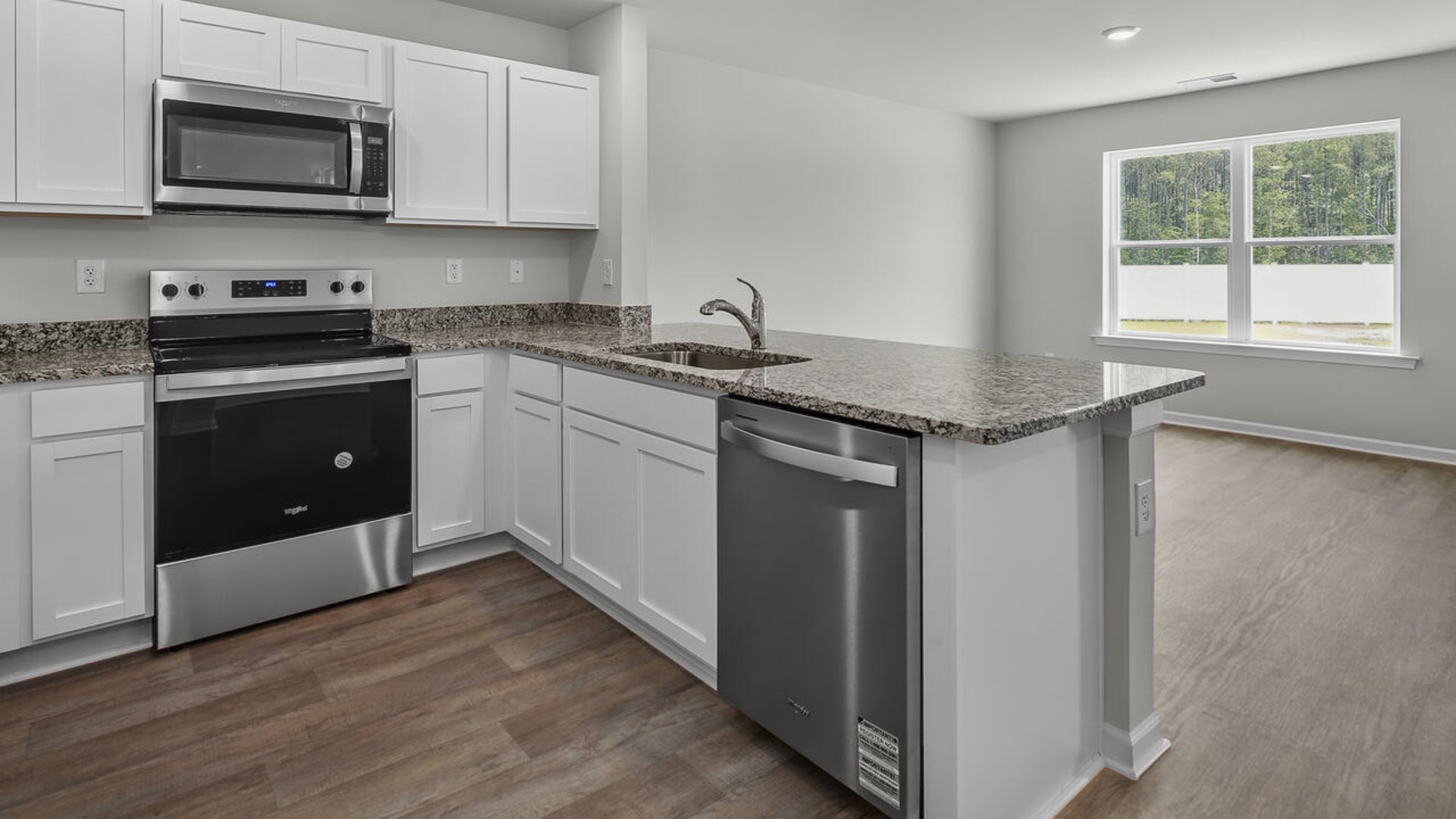 The kitchen overlooks the dining and living spaces, ideal for entertaining guests or enjoying family time while preparing meals with new stainless-steel appliances and granite countertops.