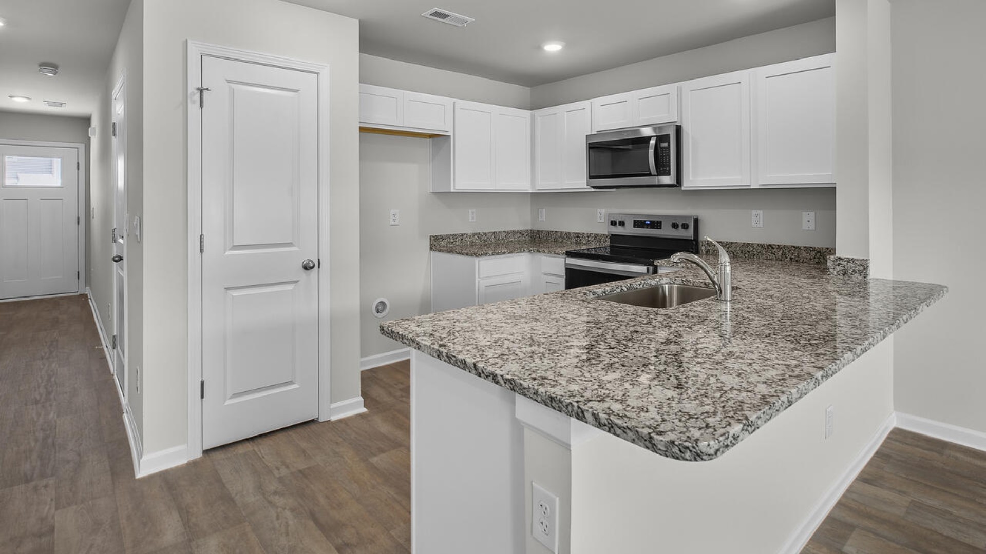 The kitchen overlooks the dining and living spaces, ideal for entertaining guests or enjoying family time while preparing meals with new stainless-steel appliances and granite countertops.