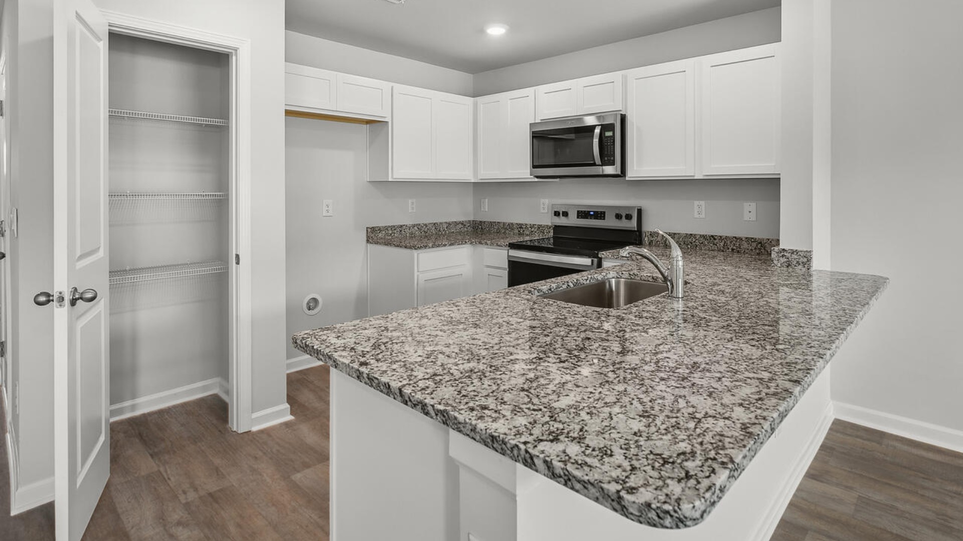 The kitchen overlooks the dining and living spaces, ideal for entertaining guests or enjoying family time while preparing meals with new stainless-steel appliances and granite countertops.