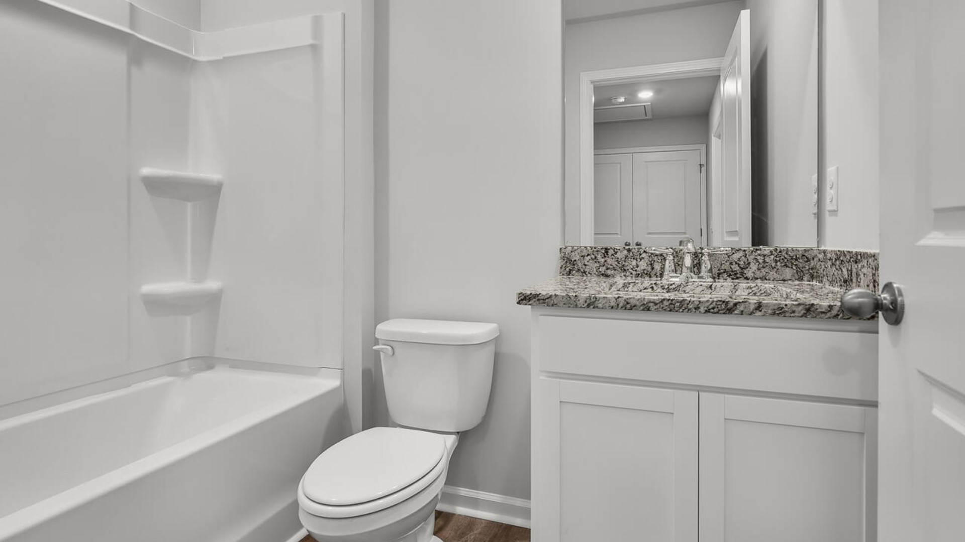 It also includes two additional bedrooms, a shared bathroom, and a laundry room for convenience. The bathrooms are equally elegant, featuring matching granite and a primary suite with a glass shower