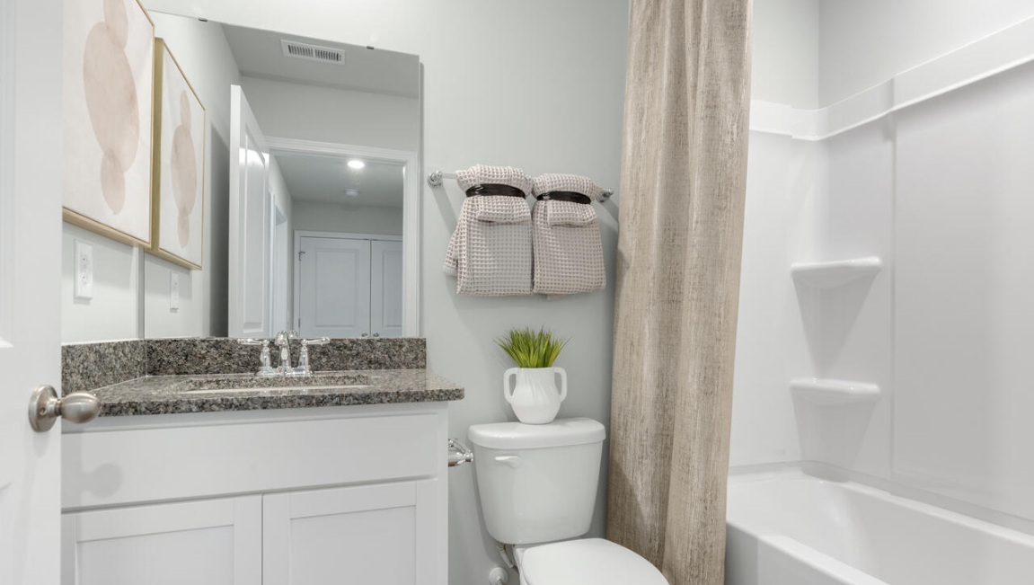 The second floor features the primary bedroom with a walk-in closet and double vanities. It also includes two additional bedrooms, a shared bathroom, and a laundry room for convenience.