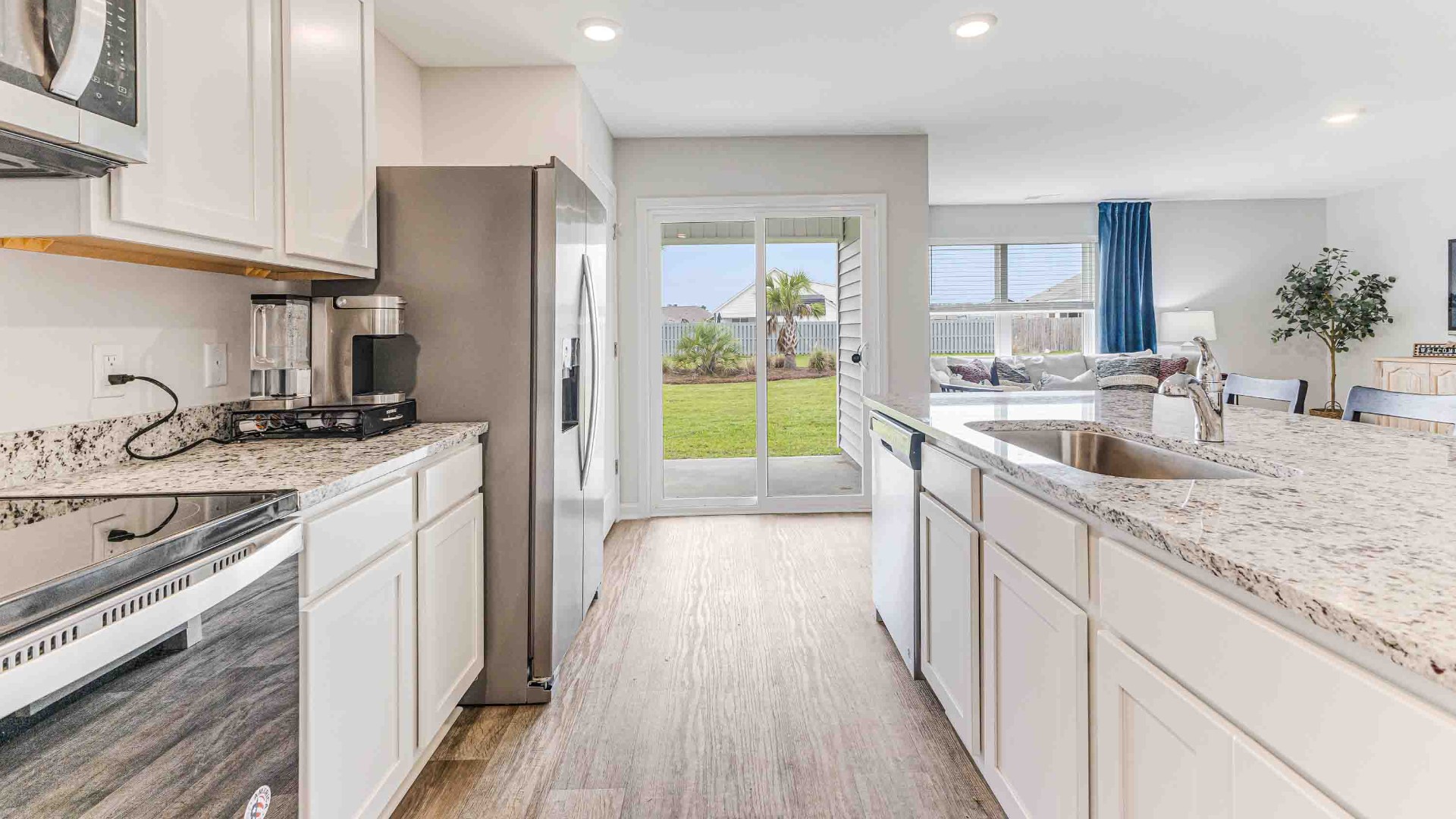 The open-concept family room, kitchen, and dining area feature granite countertops, stainless steel appliances, including a smooth-top range, dishwasher, and overhead microwave.