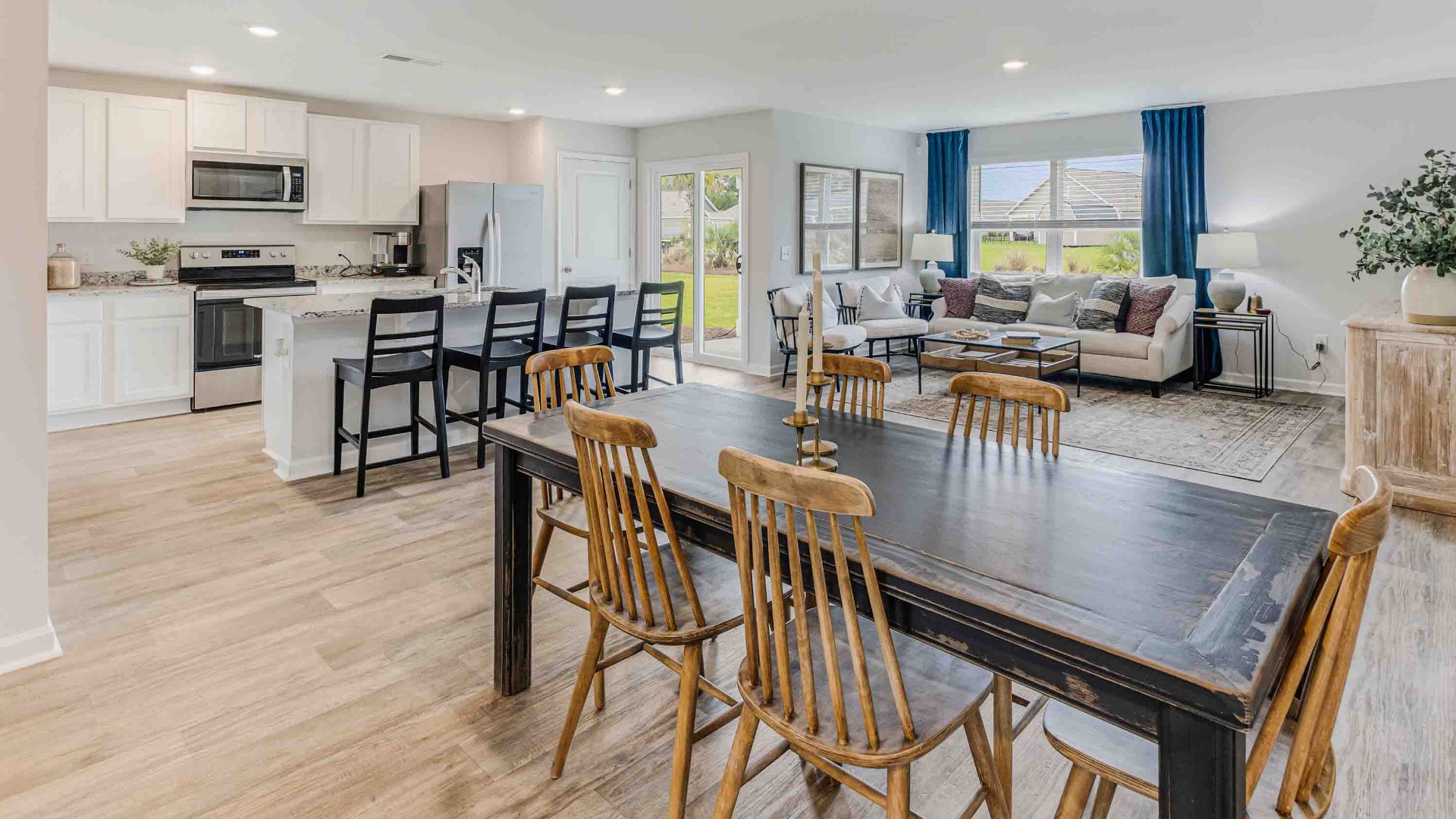 The open-concept family room, kitchen, and dining area feature granite countertops, stainless steel appliances, including a smooth-top range, dishwasher, and overhead microwave.