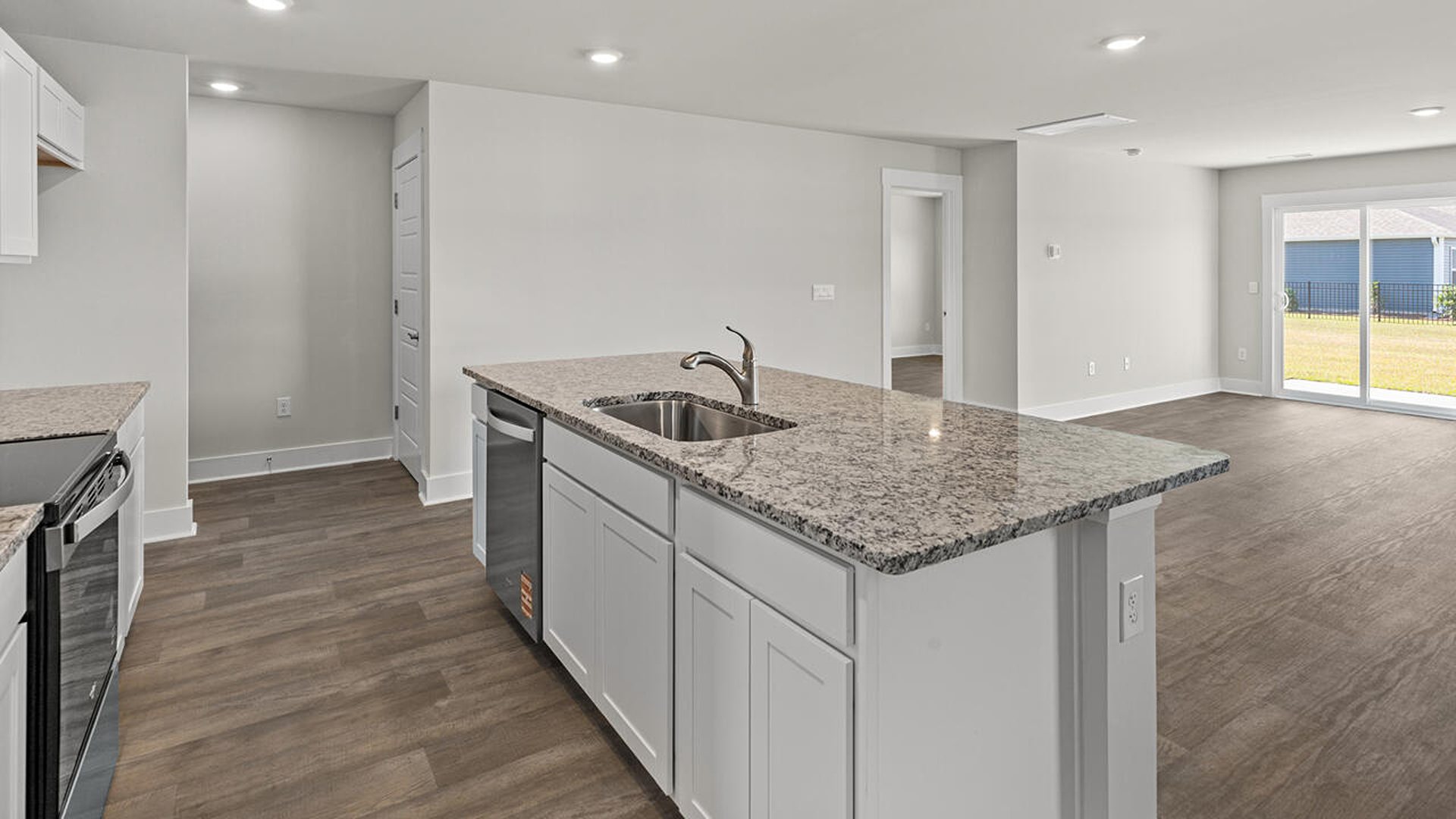 This beautiful kitchen features white cabinetry, granite counters, a large kitchen island with room for 4 counter height barstools and there's a pantry too. You’ll never be too far from the action with the living and dining area right there.