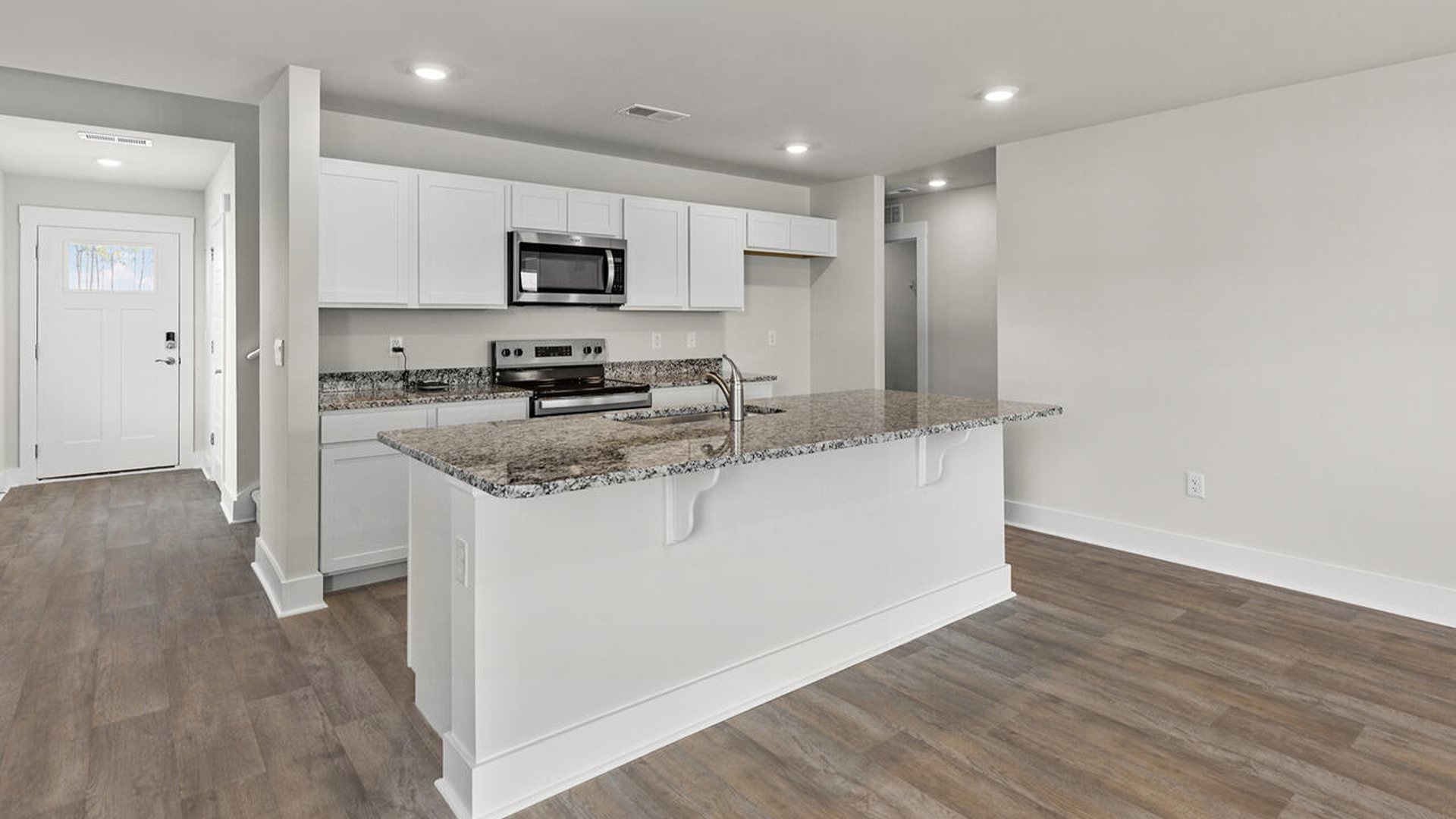This beautiful kitchen features white cabinetry, granite counters, a large kitchen island with room for 4 counter height barstools and there's a pantry too. You’ll never be too far from the action with the living and dining area right there.