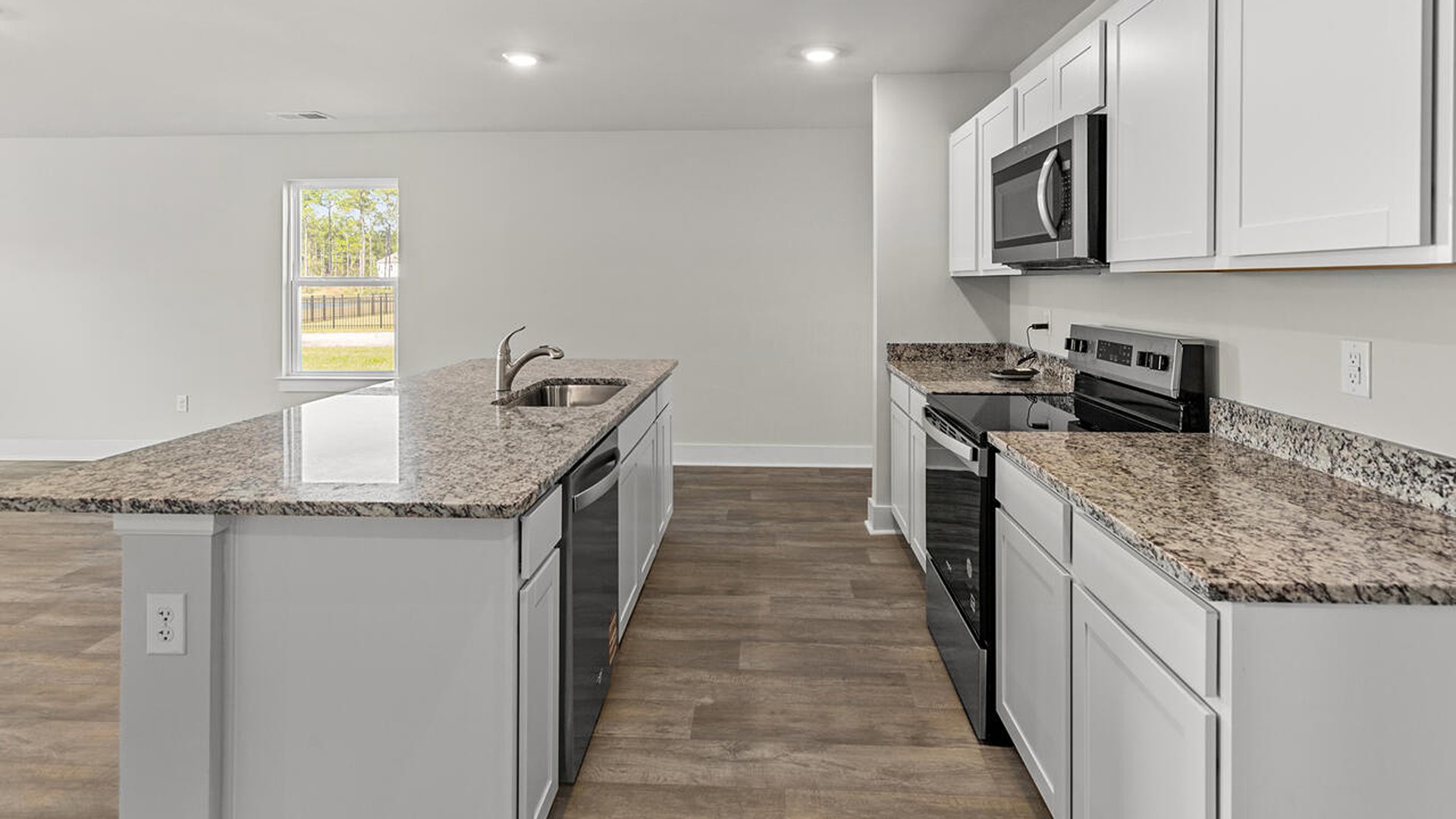 This beautiful kitchen features white cabinetry, granite counters, a large kitchen island with room for 4 counter height barstools and there's a pantry too. You’ll never be too far from the action with the living and dining area right there.