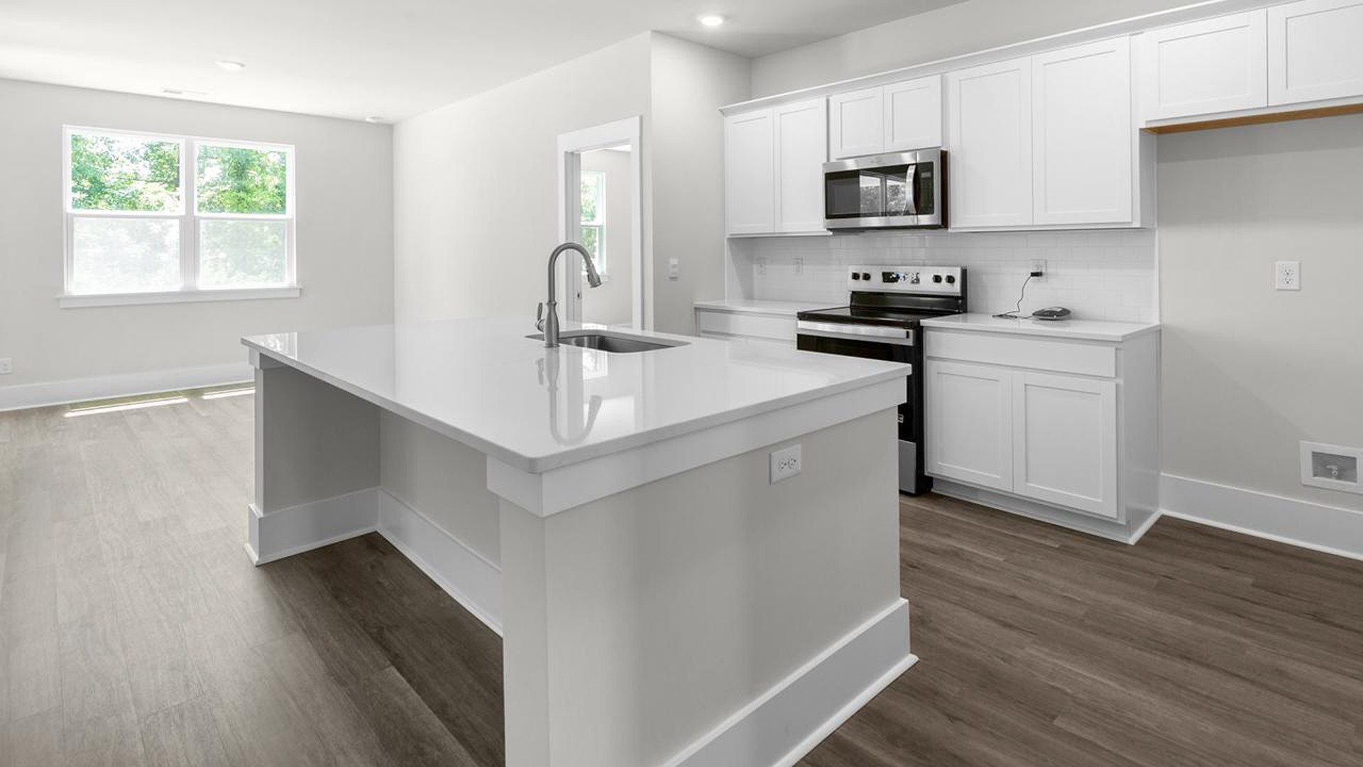 The kitchen offers quartz countertops, stainless steel appliances, a single bowl sink, and subway tile backsplash.