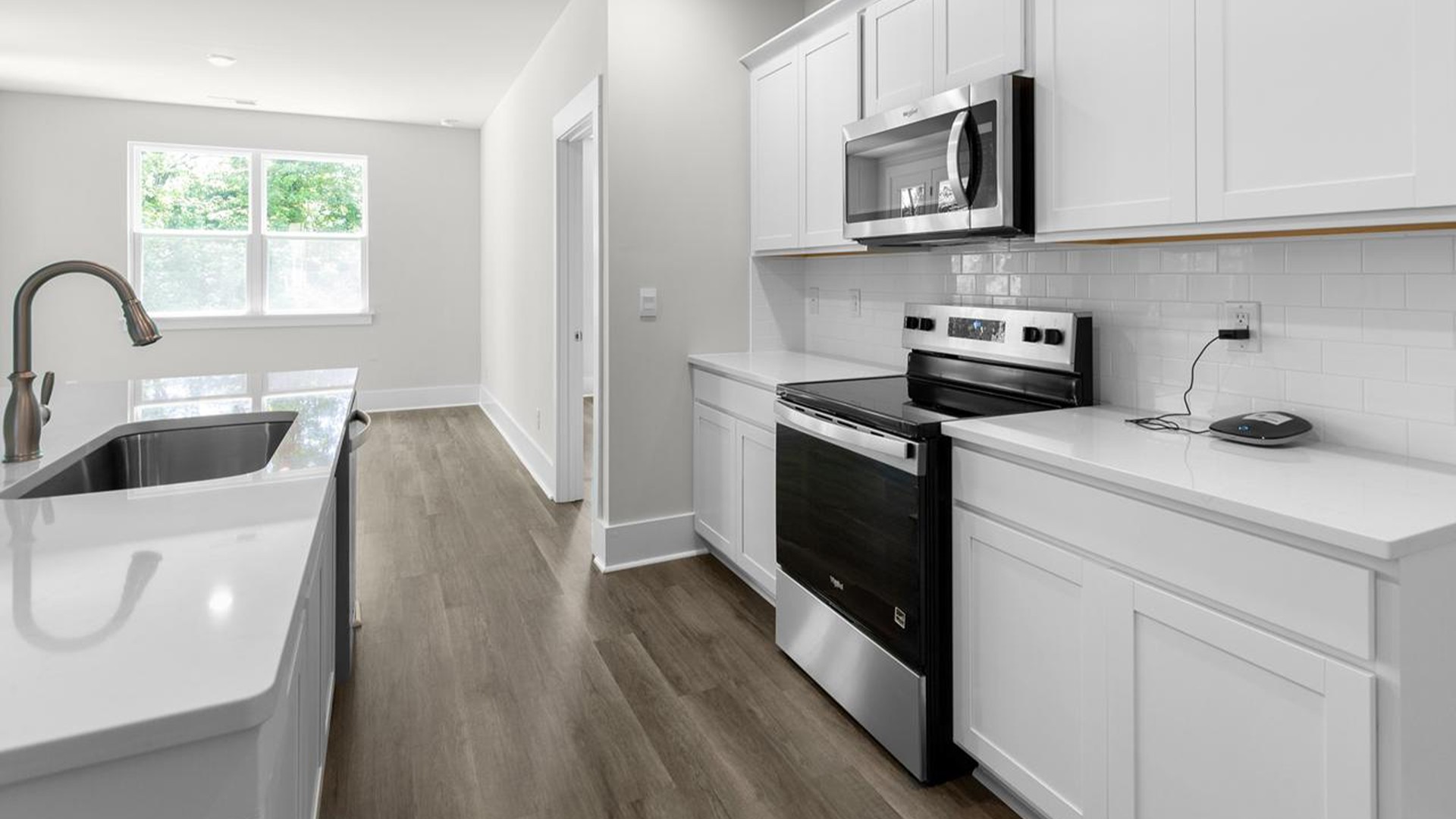 The kitchen offers quartz countertops, stainless steel appliances, a single bowl sink, and subway tile backsplash.