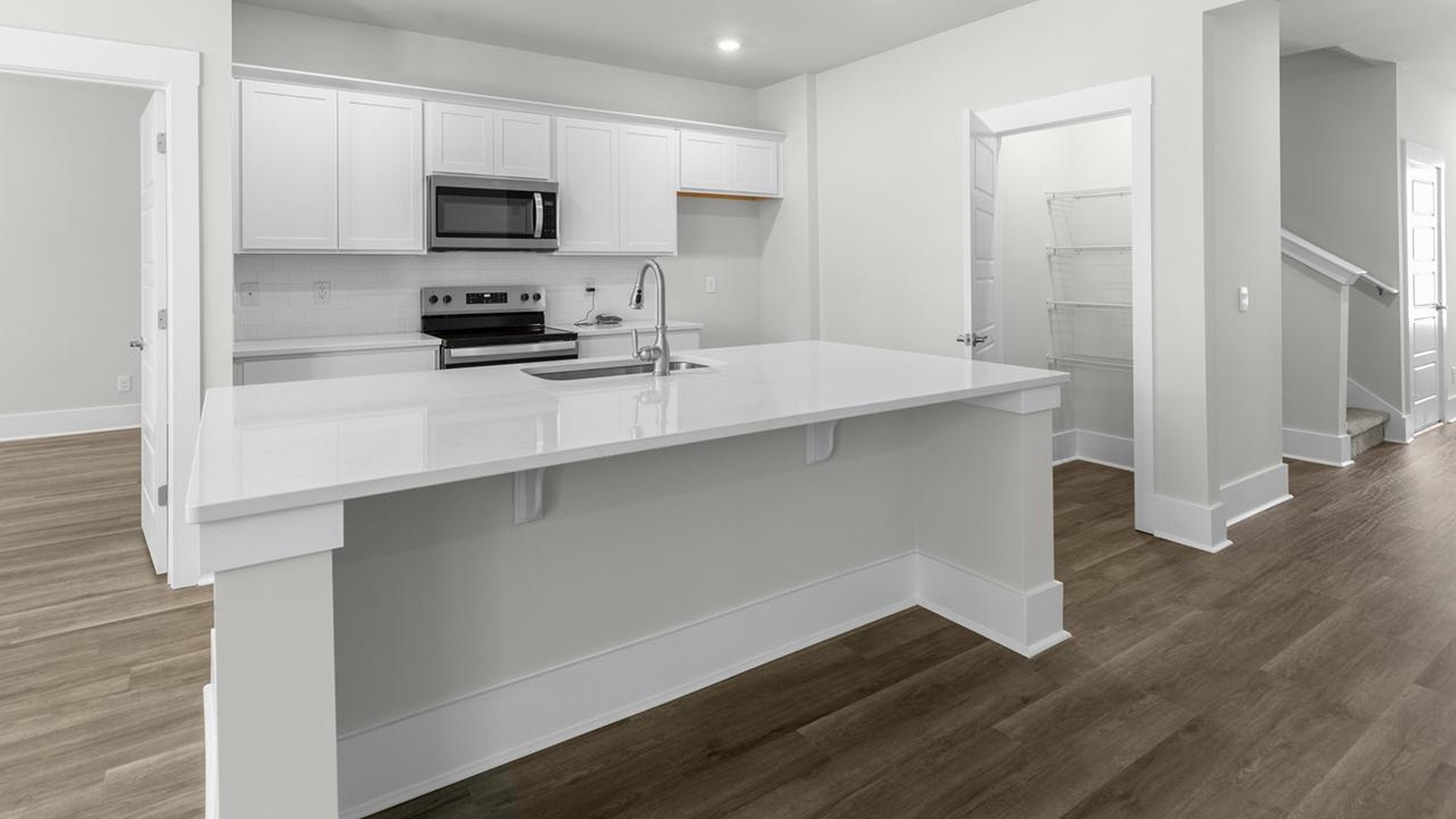 The kitchen offers quartz countertops, stainless steel appliances, a single bowl sink, and subway tile backsplash.