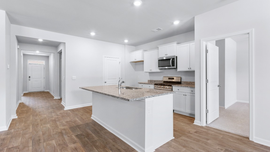 The kitchen offers quartz/granite countertops, stainless steel appliances, a single bowl sink, and subway tile backsplash. You’ll never be too far from the action with the living and dining area right there.