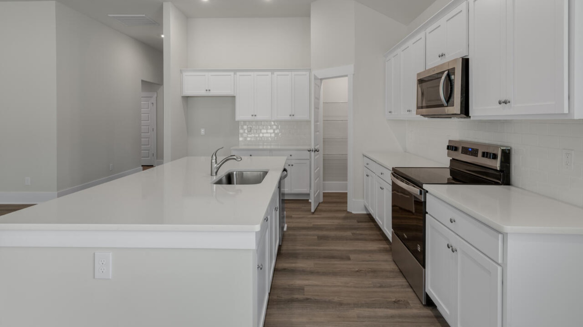 A large gourmet kitchen that features a large island, granite countertops, walk-in pantry, and stainless-steel appliances.