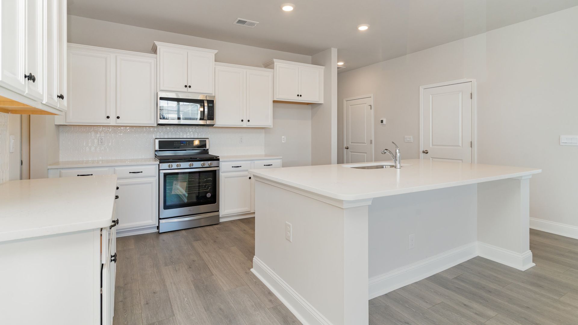 The kitchen features shaker-style cabinets, quartz countertops, and stainless steel appliances, which are sure to both turn heads and make meal prep easy. You’ll never be too far from the action with the living and dining area right there.