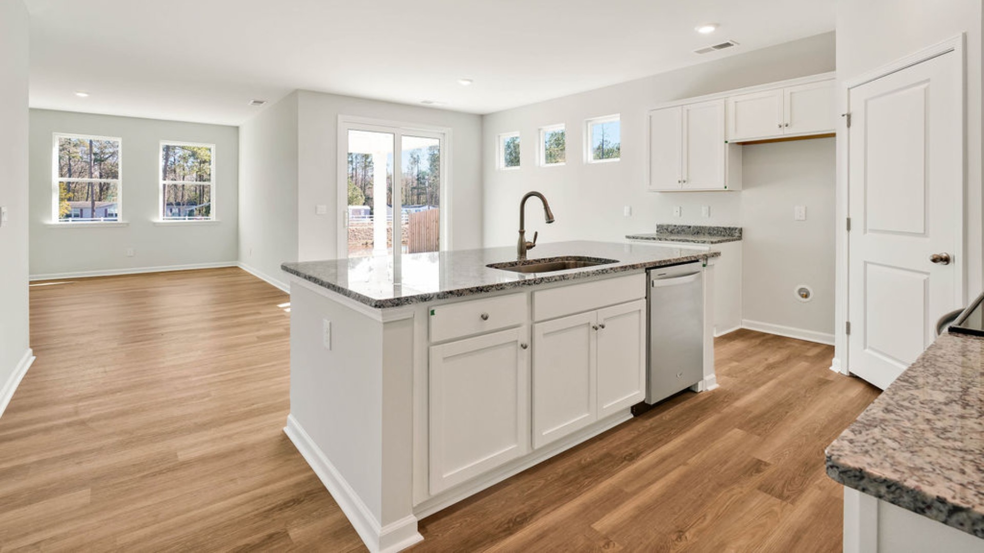 The kitchen is centered around a massive floating island with breakfast bar seating, quartz or granite countertops, and an angled corner pantry.