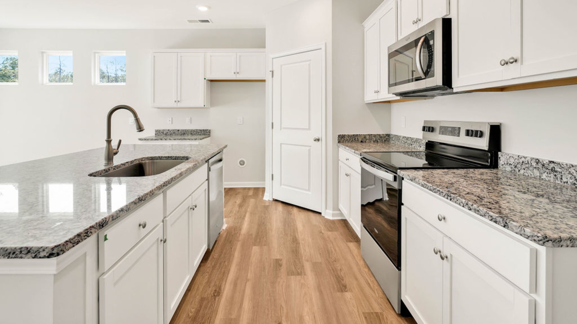 The kitchen is centered around a massive floating island with breakfast bar seating, quartz or granite countertops, and an angled corner pantry.