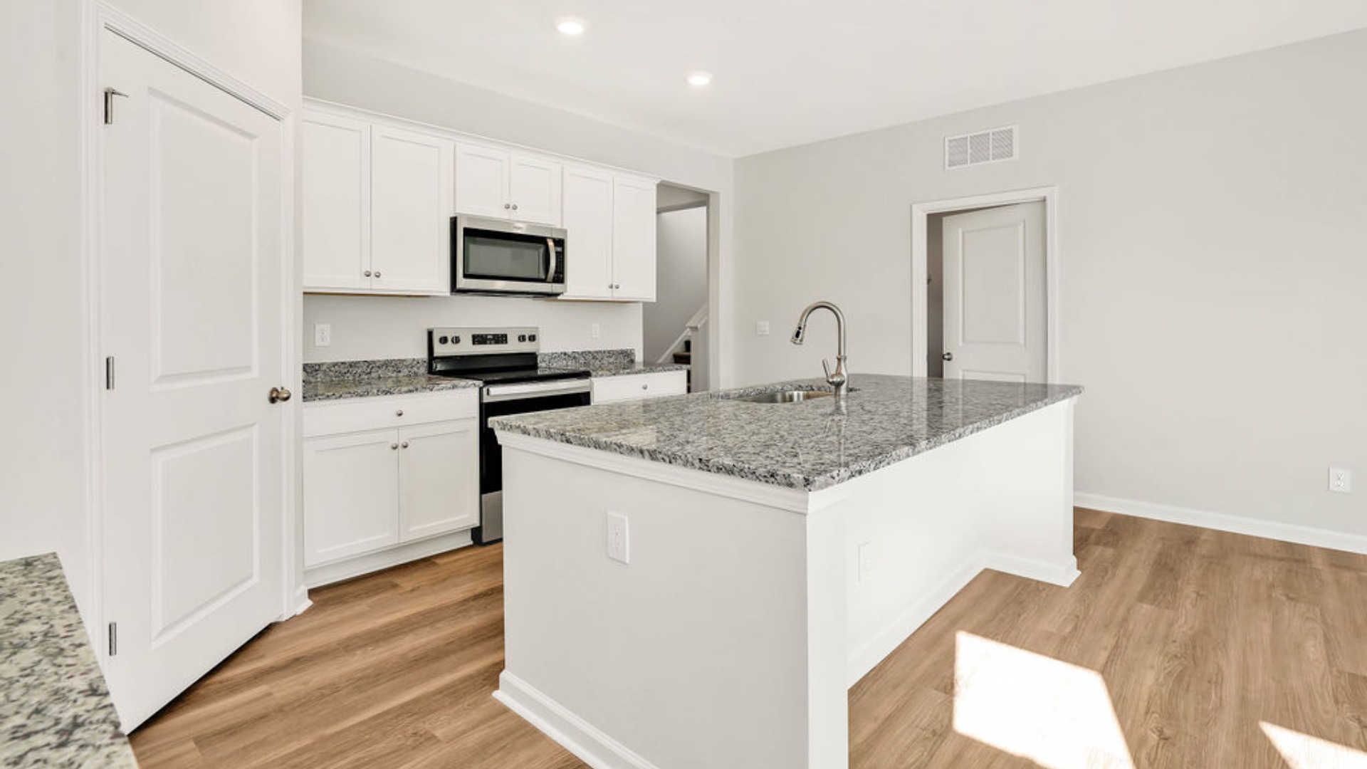 The kitchen is centered around a massive floating island with breakfast bar seating, quartz or granite countertops, and an angled corner pantry.