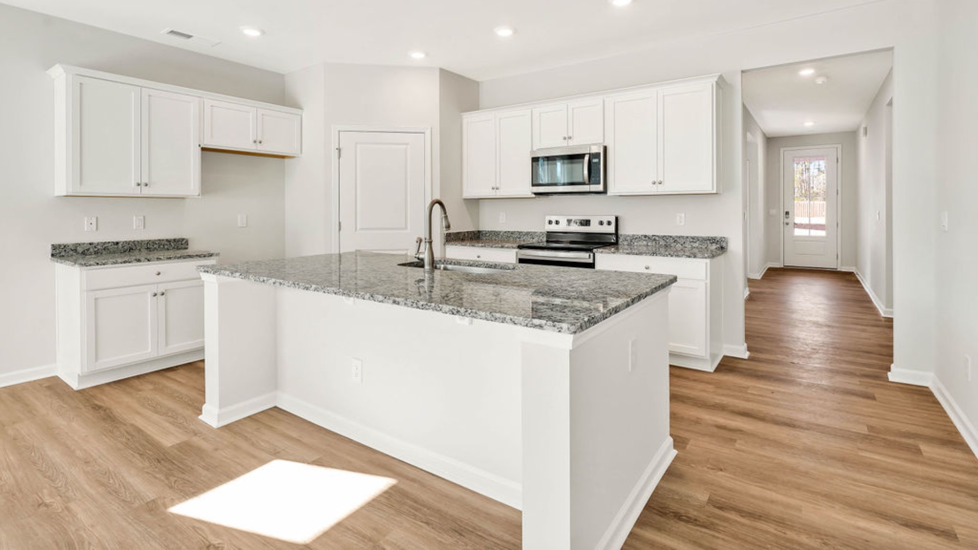 The kitchen is centered around a massive floating island with breakfast bar seating, quartz or granite countertops, and an angled corner pantry.