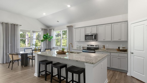 large gourmet kitchen with 36'' staggered cabinets with crown molding, granite, tile backsplash, walk-in pantry, and stainless-steel appliances in kitchen.