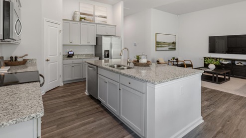 large gourmet kitchen with 36'' staggered cabinets with crown molding, granite, tile backsplash, walk-in pantry, and stainless-steel appliances in kitchen.