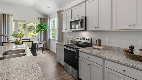 large gourmet kitchen with 36'' staggered cabinets with crown molding, granite, tile backsplash, walk-in pantry, and stainless-steel appliances in kitchen.