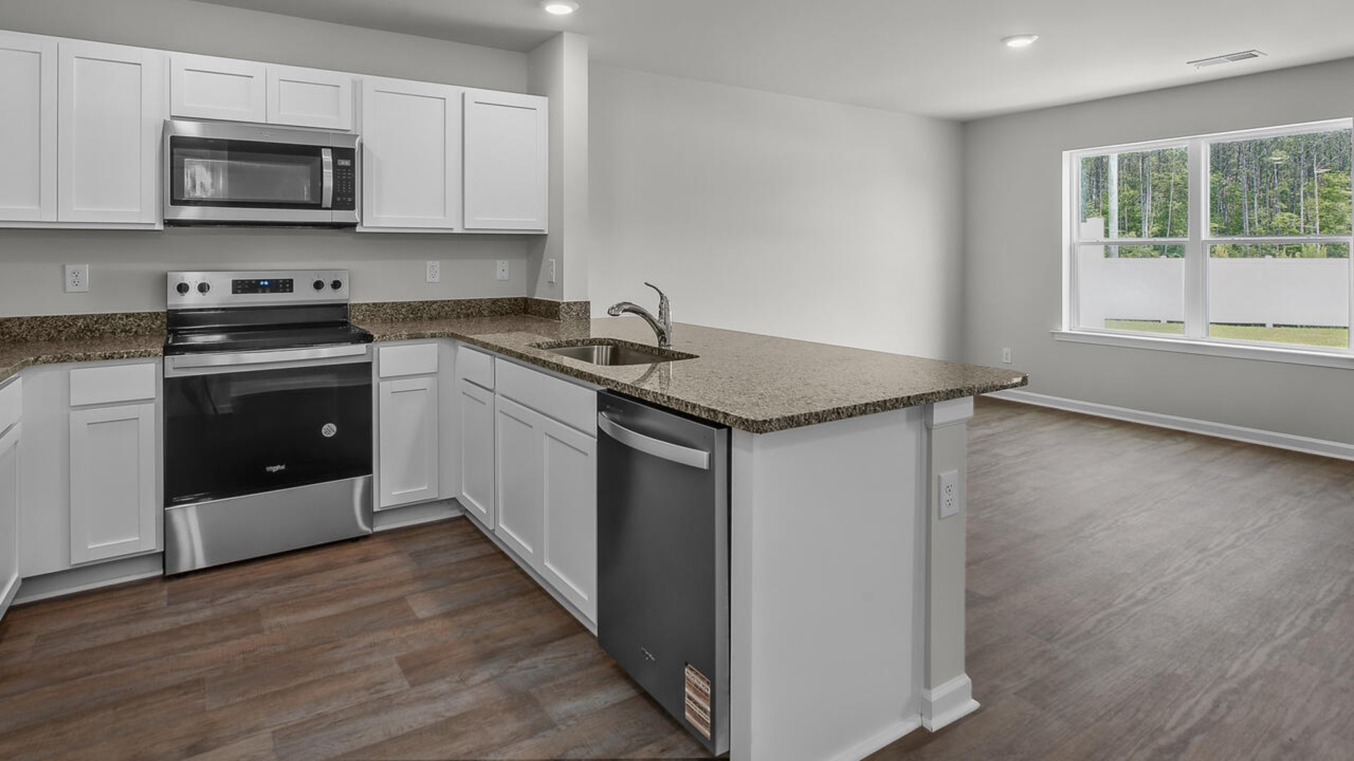 The kitchen overlooks the dining and living spaces, ideal for entertaining guests or enjoying family time while preparing meals with new stainless-steel appliances and Granite countertops.