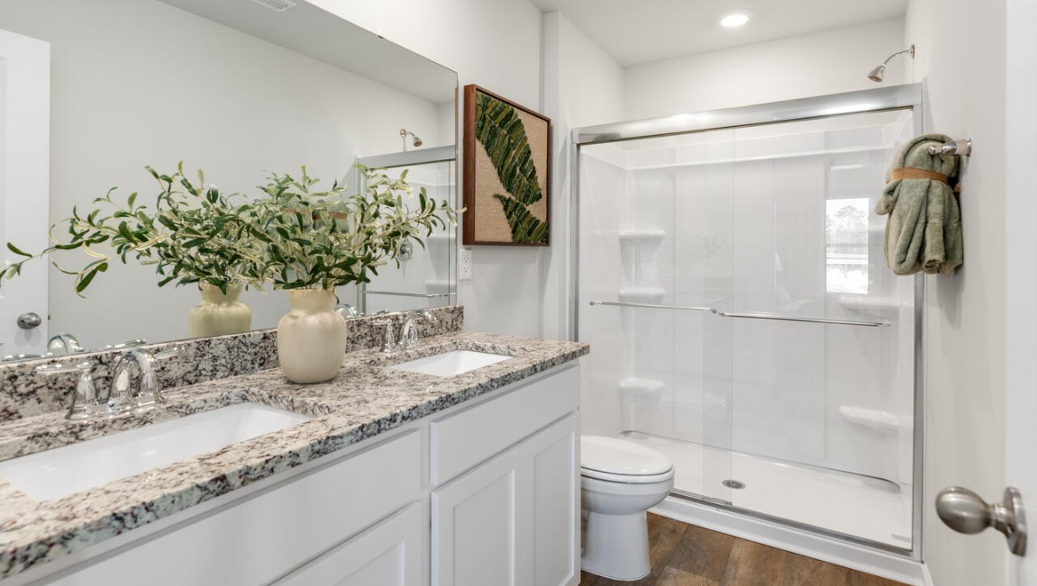 The first floor features a spacious primary bedroom, offering convenience and privacy.  The primary bathroom boasts a luxurious glass-enclosed shower and granite countertops