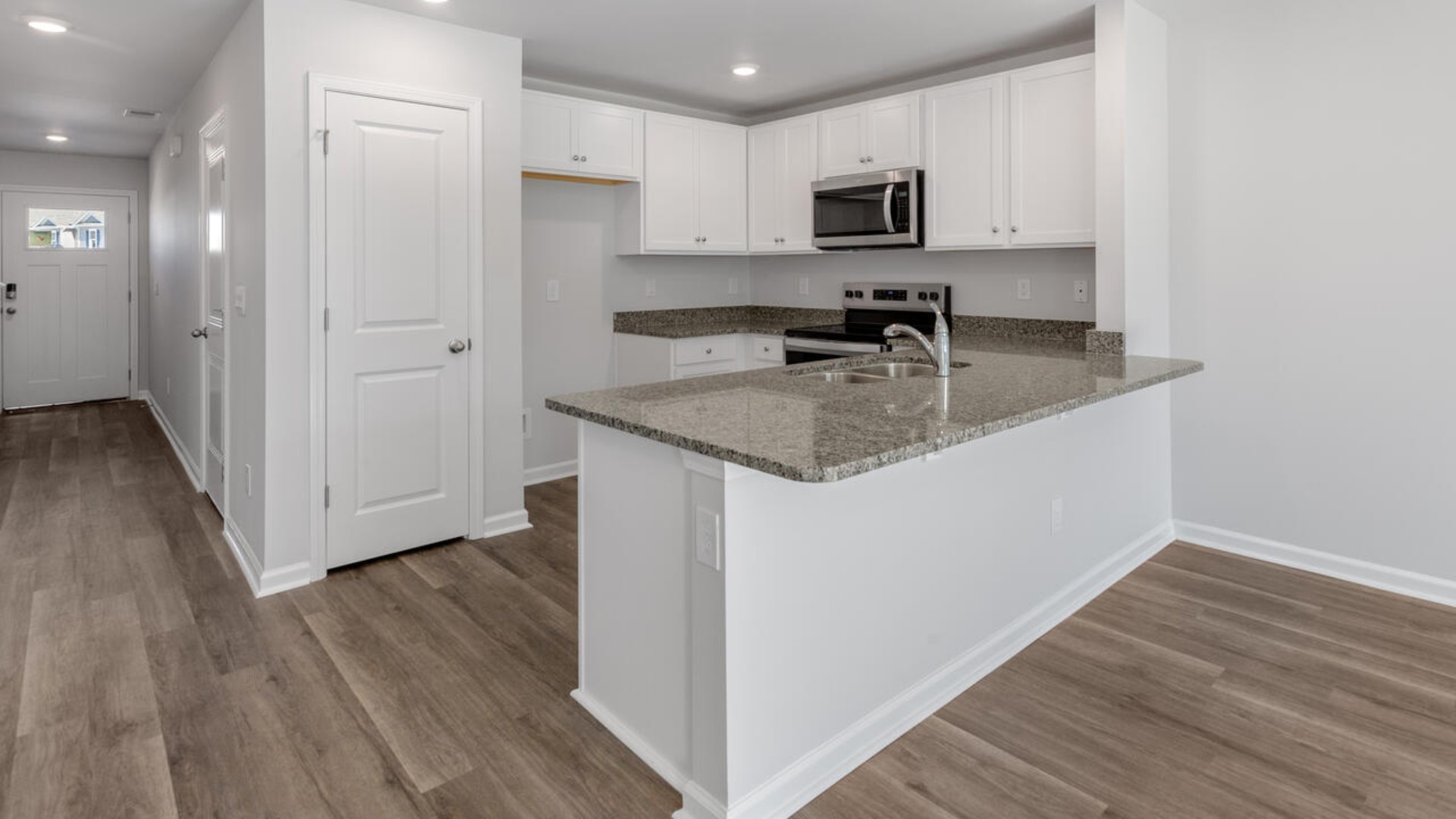The kitchen overlooks the dining and living spaces, ideal for entertaining guests or enjoying family time while preparing meals with new stainless-steel appliances and granite countertops.