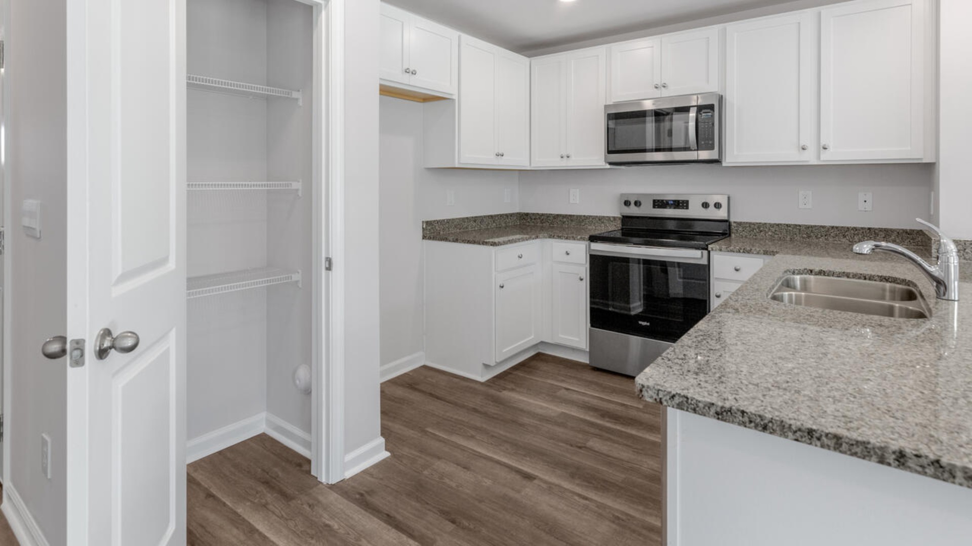 The kitchen overlooks the dining and living spaces, ideal for entertaining guests or enjoying family time while preparing meals with new stainless-steel appliances and granite countertops.
