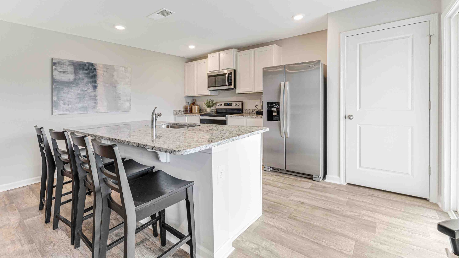 The open-concept family room, kitchen, and dining area feature Granite countertops, stainless steel appliances, including a smooth-top range, dishwasher and overhead microwave