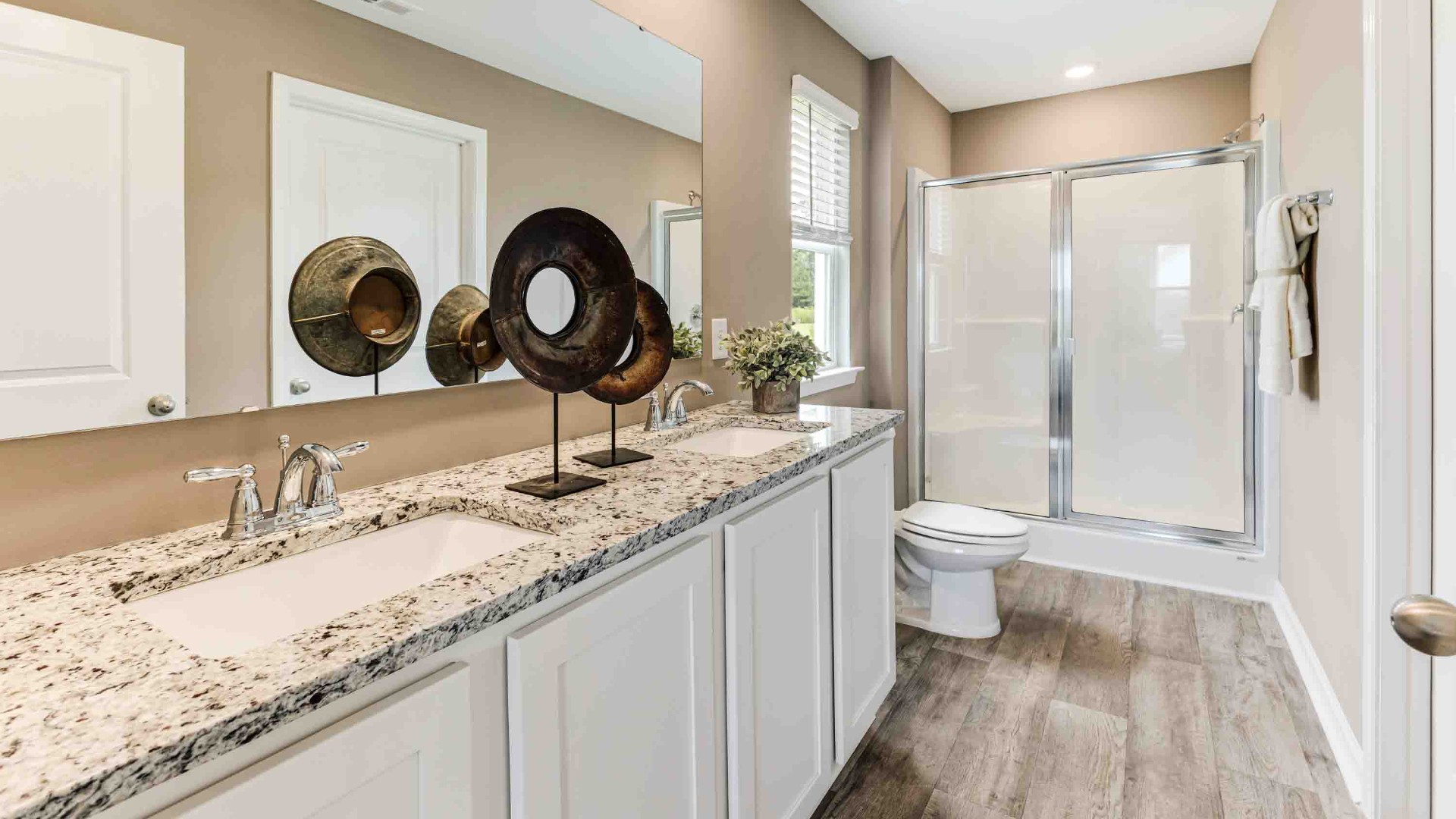 At the back, the Primary Suite provides privacy with a large walk-in closet and walk-in shower. This floor plan combines comfort and convenience, making it a great choice for those seeking an open layout and a 2-car garage.