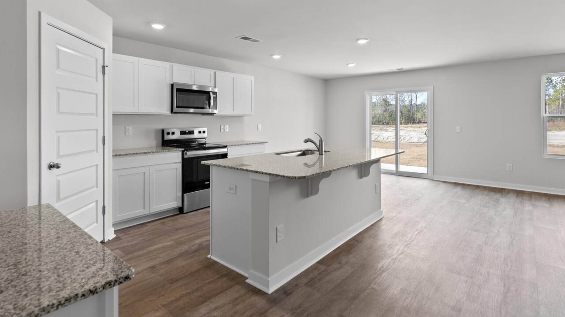 he open-concept kitchen features granite countertops and stainless-steel appliances. The kitchen seamlessly connects to the dining and living areas,
