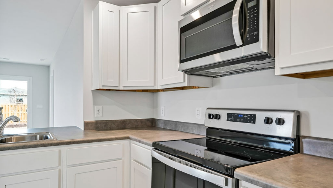 The kitchen is equipped for both efficiency and style with all stainless-steel appliances, including a range, built-in dishwasher, refrigerator, and microwave.