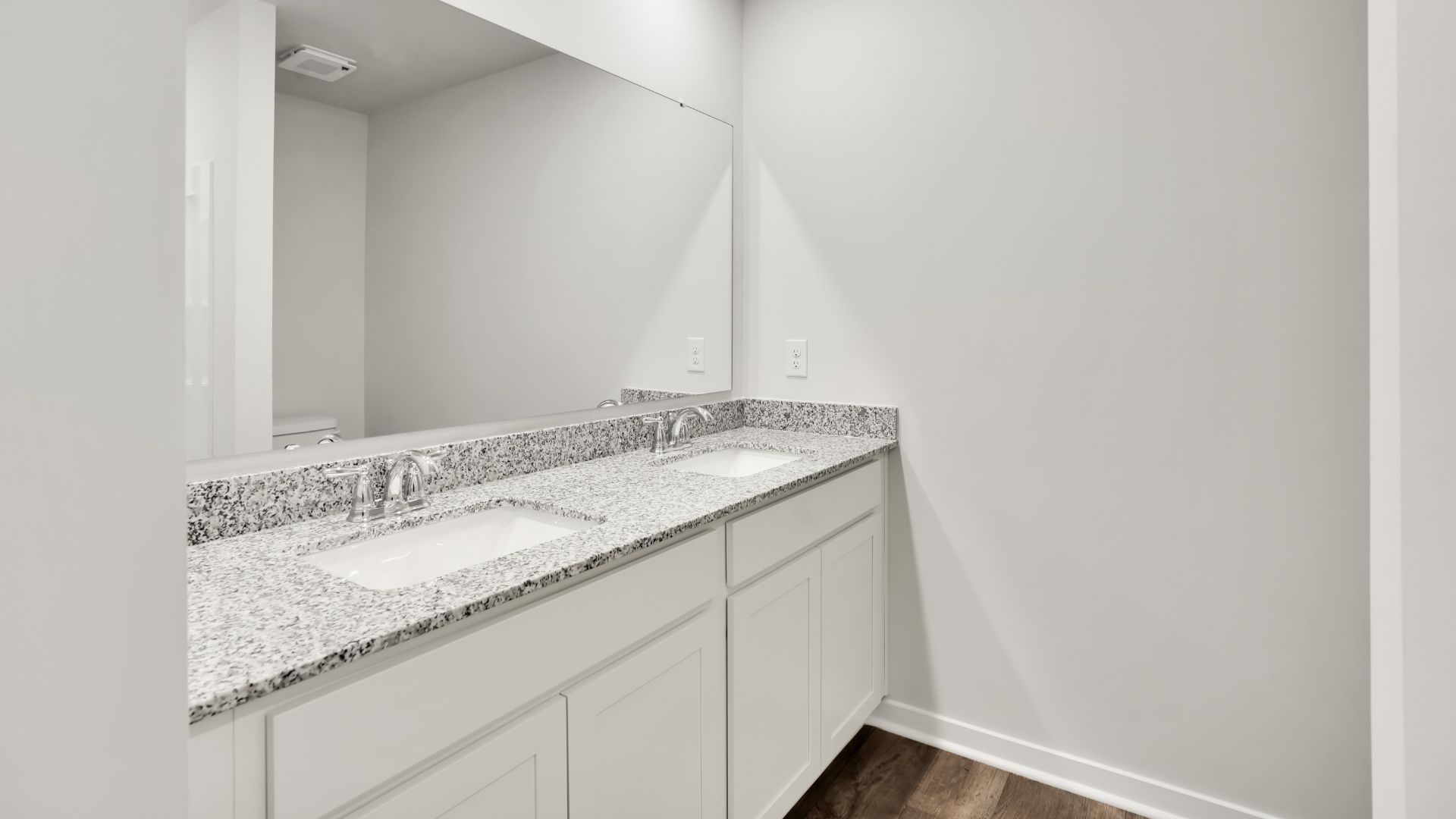 The primary bedroom features an ensuite bathroom with a double vanity, granite countertops, and walk-in closet. Each bedroom has vinyl flooring along with a closet that are versatile to fit your family's needs, whether they become bedrooms or home offices.
