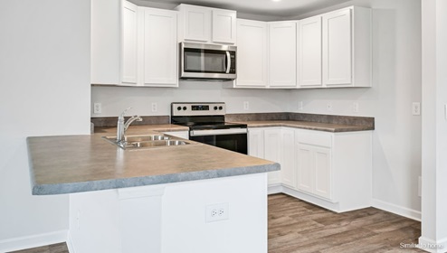 The kitchen is equipped for both efficiency and style with all stainless-steel appliances, including a range, built-in dishwasher, refrigerator, and microwave.