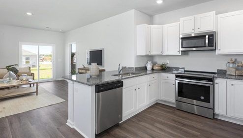 The kitchen is equipped for both efficiency and style with all stainless-steel appliances, including a range, built-in dishwasher, refrigerator, and microwave.