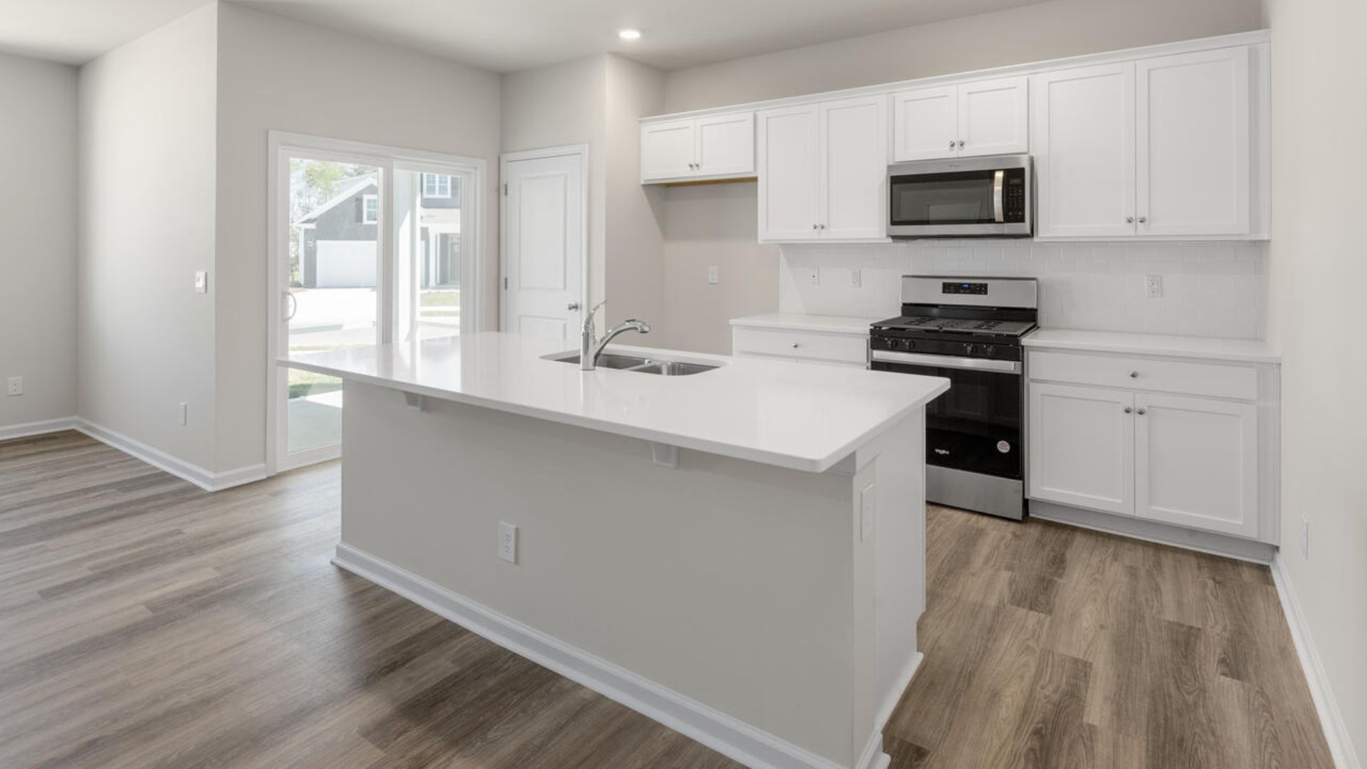 The open-concept family room, kitchen, and dining area feature granite countertops, stainless steel appliances, including a smooth-top range, dishwasher and overhead microwave.