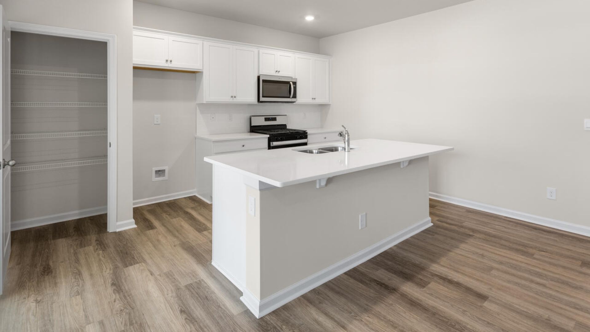 The open-concept family room, kitchen, and dining area feature granite countertops, stainless steel appliances, including a smooth-top range, dishwasher and overhead microwave.