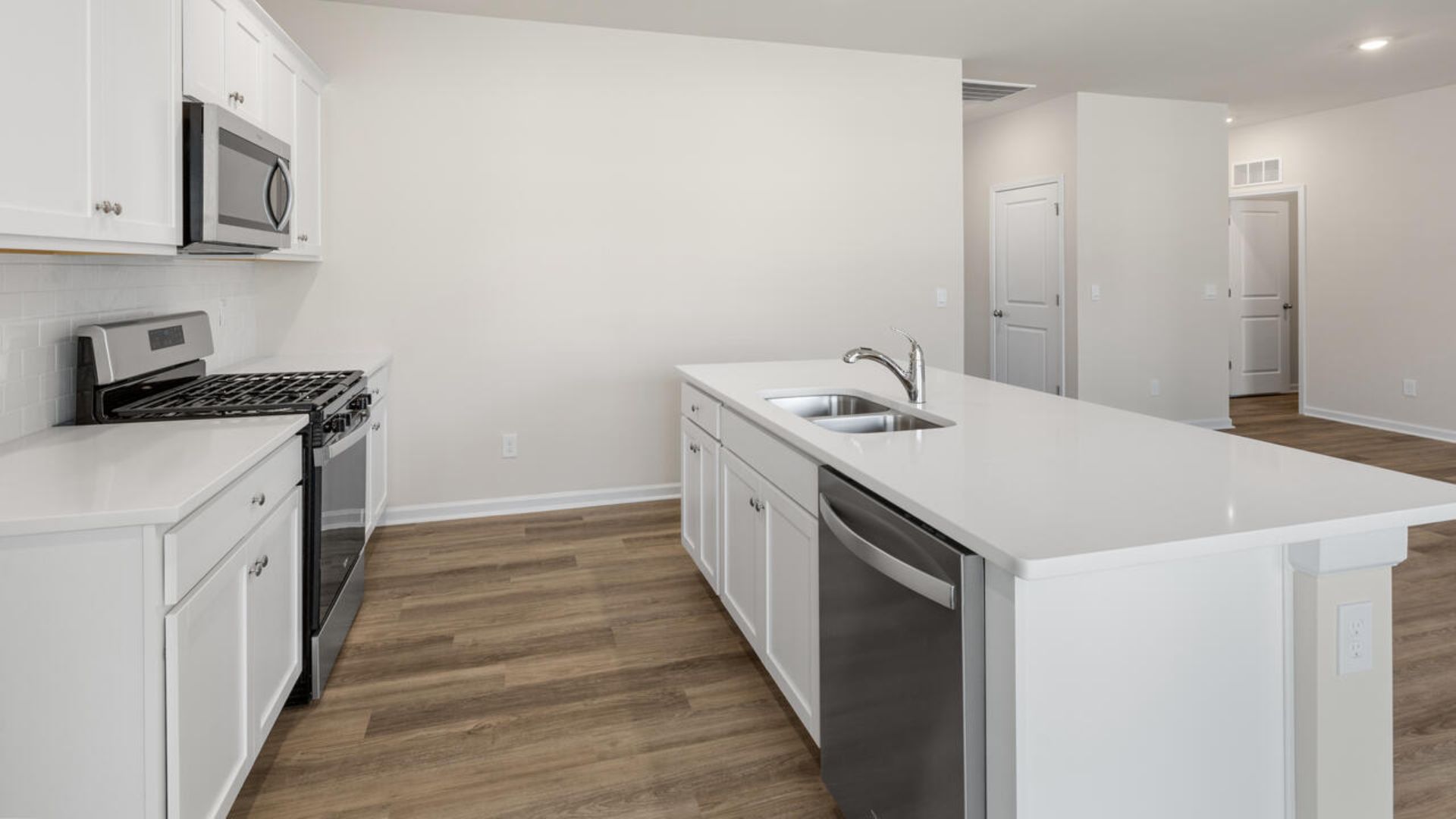 The open-concept family room, kitchen, and dining area feature granite countertops, stainless steel appliances, including a smooth-top range, dishwasher and overhead microwave.