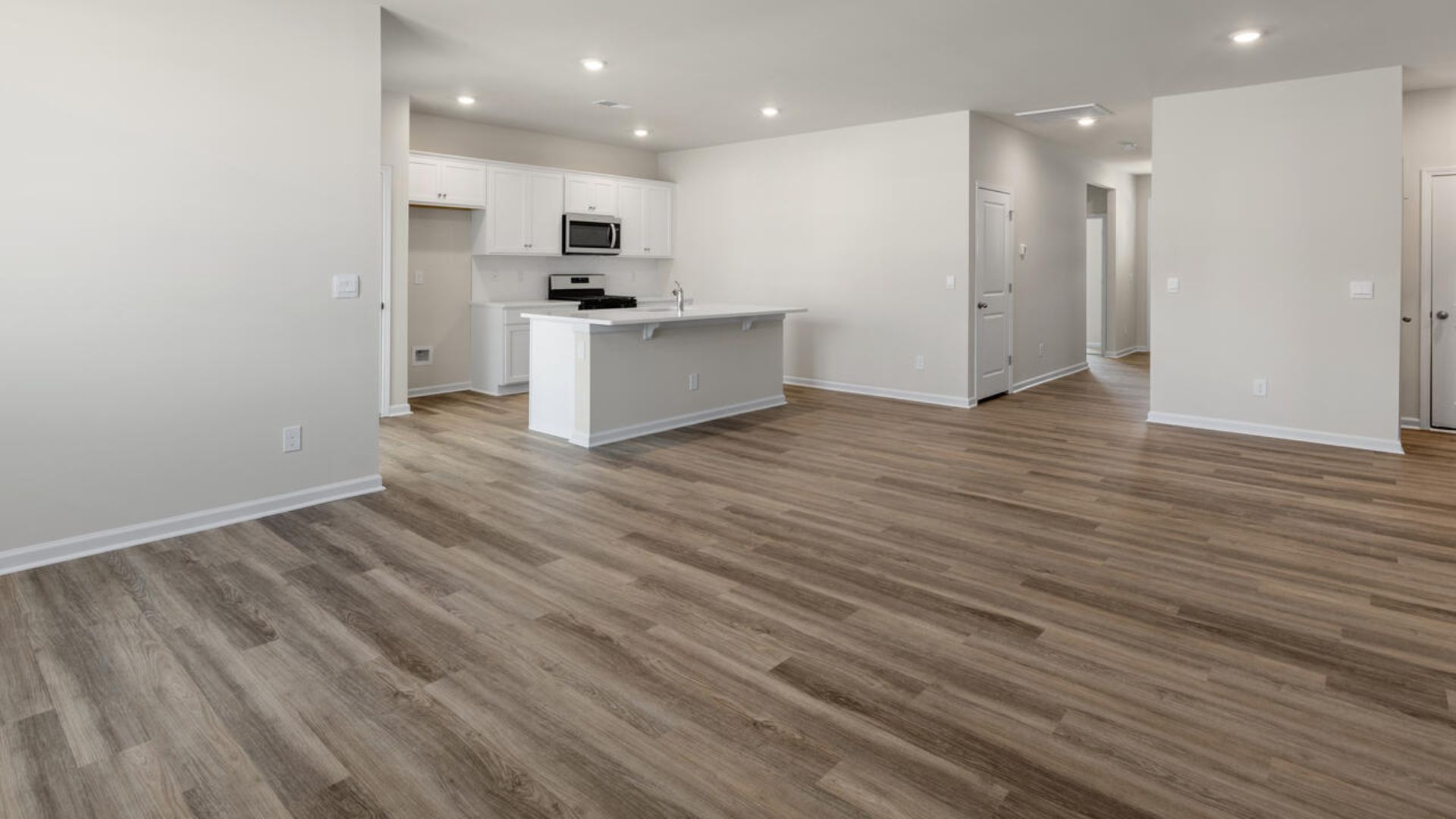 The open-concept family room, kitchen, and dining area feature granite countertops, stainless steel appliances, including a smooth-top range, dishwasher and overhead microwave.