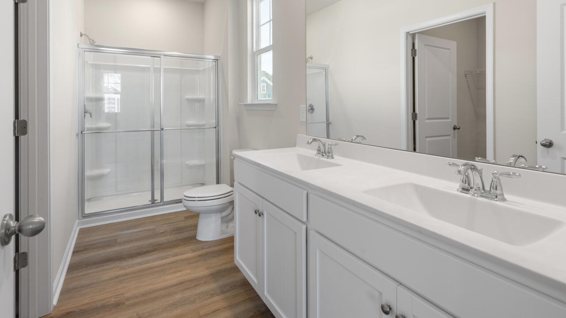 At the back, the Primary Suite provides privacy with a large walk-in closet and walk-in shower. This floor plan combines comfort and convenience, making it a great choice for those seeking an open layout and a 2-car garage.