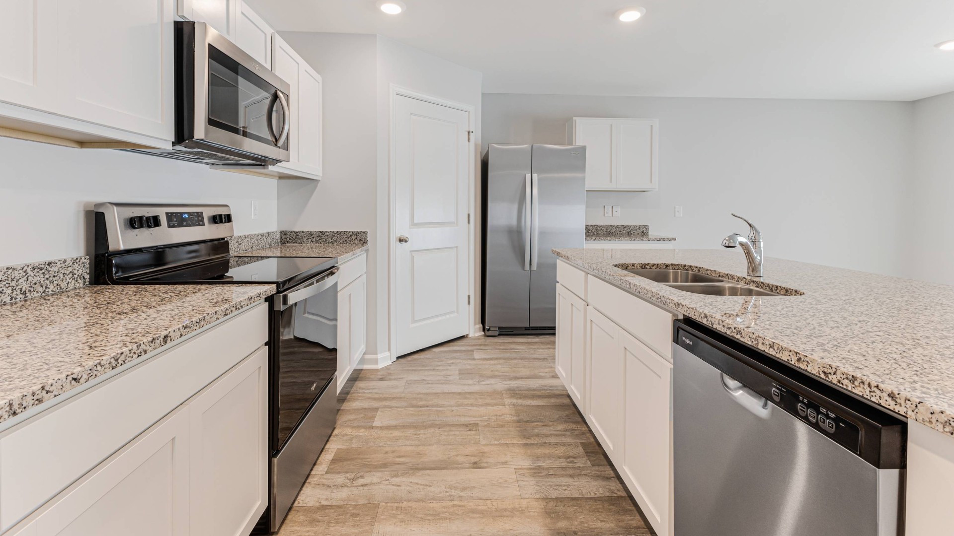 A fantastic kitchen featuring Whirlpool Stainless Steel Appliances with a smooth-top electric range, microwave, dishwasher.