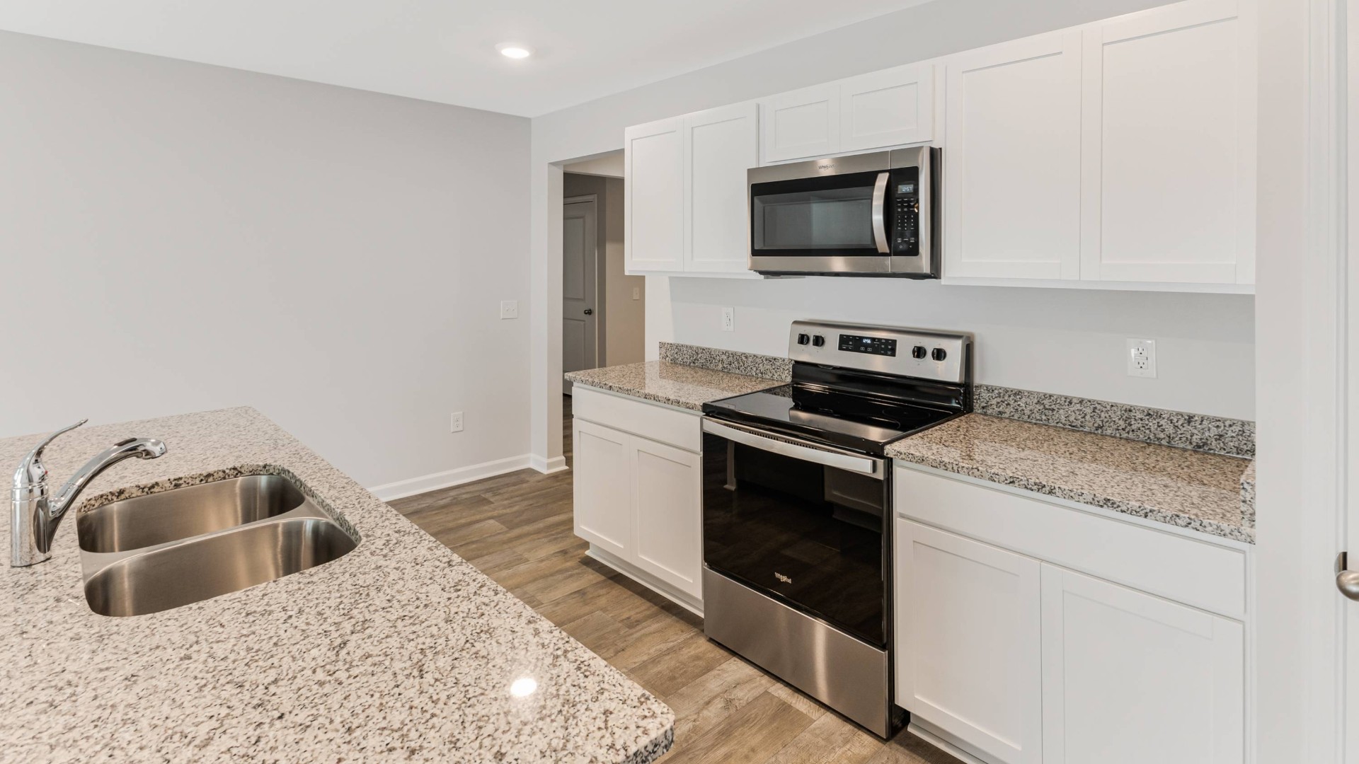 A fantastic kitchen featuring Whirlpool Stainless Steel Appliances with a smooth-top electric range, microwave, dishwasher.