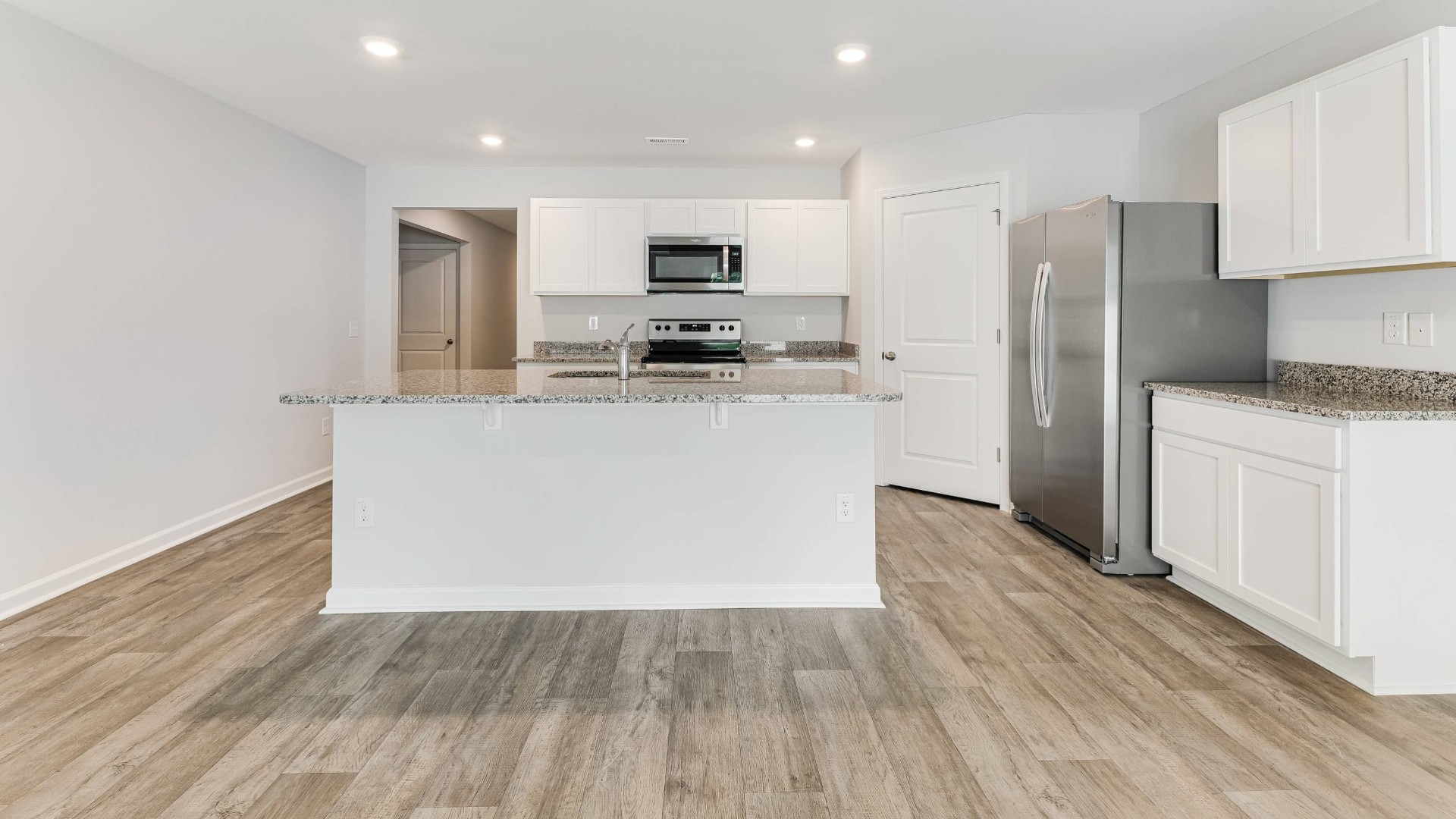 A fantastic kitchen featuring Whirlpool Stainless Steel Appliances with a smooth-top electric range, microwave, dishwasher.